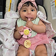 Arleth is registered to the contest to win money with this photo: baby, infant, car_seat, pink_headband, pink_tutu, toy, pacifier, blanket, clothing, hand, face, person, cute, sitting, indoors, child, expression, cute_outfit, soft_toy, closeup