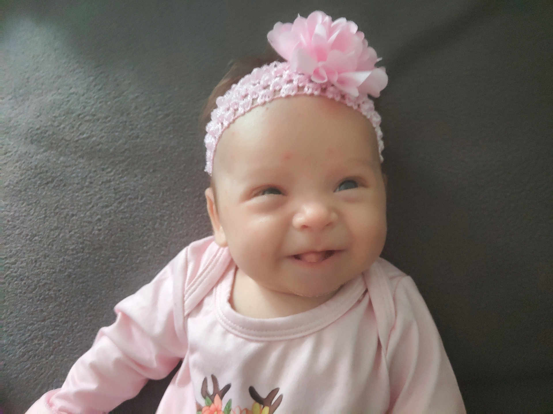 Alba participe au concours pour gagner de l'argent avec cette photo : baby, infant, smile, headband, flower, pink_clothing, pink_headband, tongue_out, cute, portrait, child, person, indoors, soft_background, face, young_child, happy, baby_girl, headshot, closeup