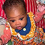 baby, infant, child, face, eyes, clothing, floral_pattern, orange, blue, socks, blanket, pillow, indoor, cute, portrait, skin, hands, sitting, person, young