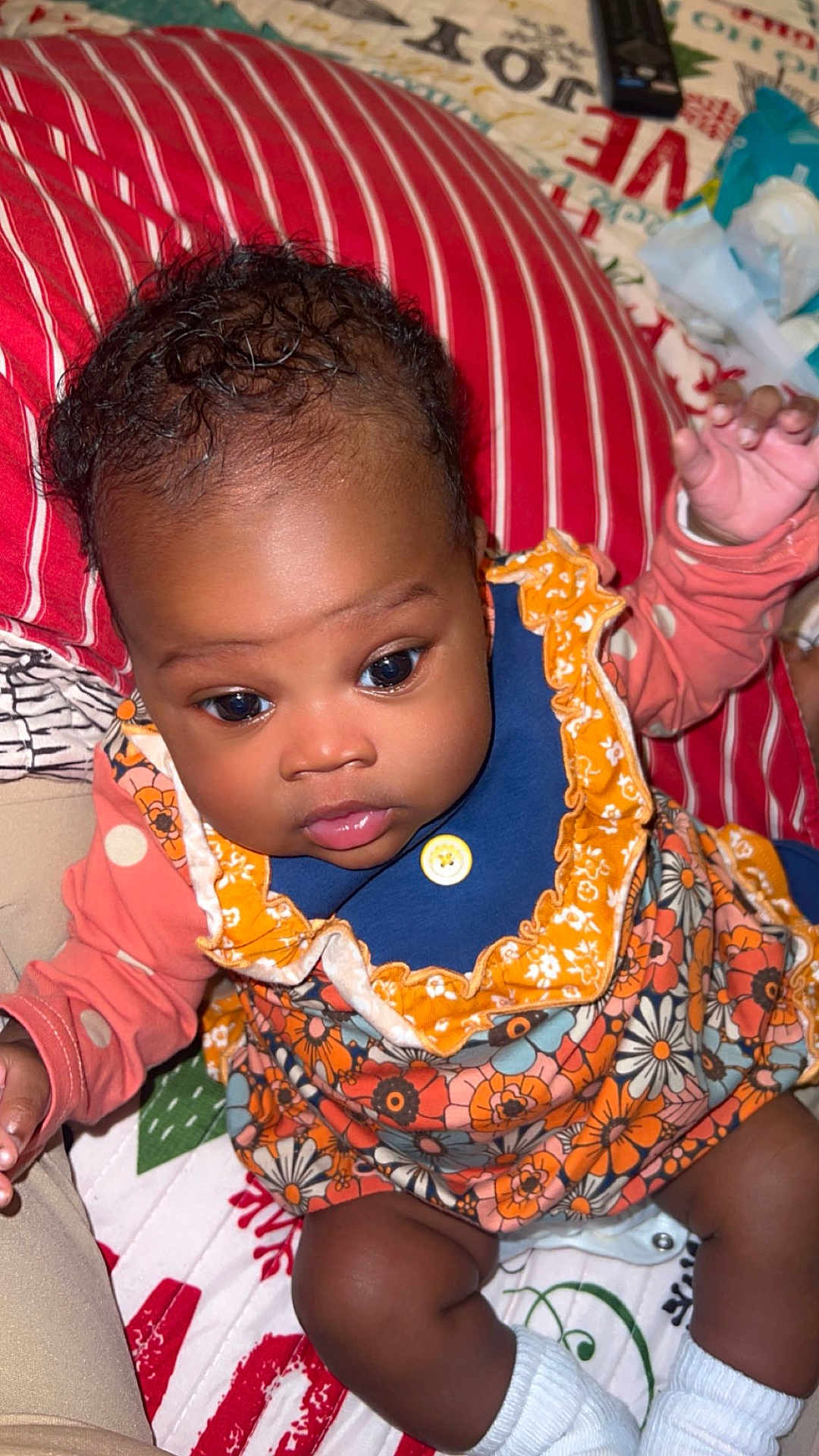 Kehlani joined the competition — help win amazing prizes! baby, infant, child, face, eyes, clothing, floral_pattern, orange, blue, socks, blanket, pillow, indoor, cute, portrait, skin, hands, sitting, person, young