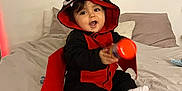 Kamil a rejoint le concours — aidez-le/la à gagner de superbes lots ! baby, child, costume, bat, red, black, bed, pillow, smiling, indoors, toy, cute, wall_art, happy, sitting, clothing, footwear, headwear, person, infant