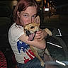 american_flag_shirt, animal, bench, casual_clothing, dark_background, dog, face, happy, hugging, joy, light, nighttime, outdoor, person, pet, red_hair, shorts, smiling, tongue_out, woman