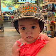 Chloe is registered to the contest to win money with this photo: toddler, child, hat, camo, indoors, store, camping, clothing, person, baby, face, portrait, red_dress, strawberry, arm, holding, expressionless, shopping, sleeveless, cute