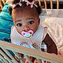 Cherish is registered to the contest to win money with this photo: baby, pacifier, crib, bows, blanket, infant, child, cute, indoors, sleeping_area, clothing, hand, portrait, person, baby_girl, bed, soft_toys, colorful, closeup, curious