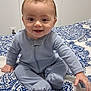 Colton joined the competition — help win amazing prizes! baby, bed, blue, child, cute, face, footed_pajamas, hair, hand, happy, indoor, infant, mohaawk, pajamas, patterned_blanket, person, sitting, skin, smiling, young_child