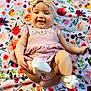 Layla is registered to the contest to win money with this photo: baby, child, smiling, headband, bow, dress, sock, footwear, floral_pattern, blanket, happy, playful, infant, cute, portrait, lying_down, skin, hand, colorful, indoors