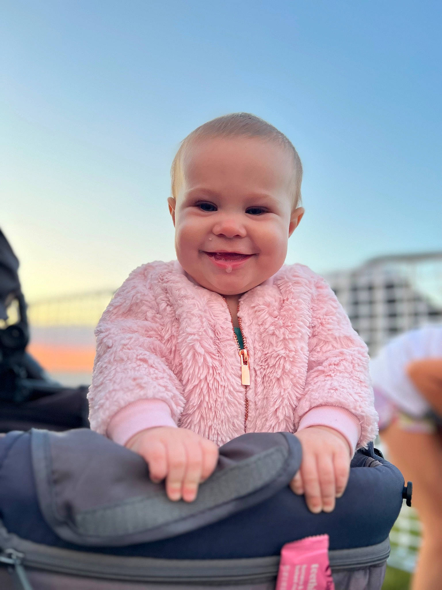 Emilia is registered to the contest to win money with this photo: baby, baby_toddler_clothing, cheek, comfort, eye, facial_expression, finger, flash_photography, fun, gesture, happy, joy, leisure, people_in_nature, person, sitting, skin, sky, sleeve, smile