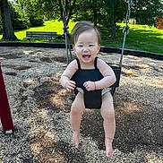 Esol joined the competition — help win amazing prizes! toddler, child, swing, playground, outdoor, smiling, happy, baby, wood_chips, tree, bench, sunlight, grass, summer, fun, park, seat, person, nature, daytime