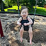 toddler, child, swing, playground, outdoor, smiling, happy, baby, wood_chips, tree, bench, sunlight, grass, summer, fun, park, seat, person, nature, daytime
