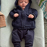 Isaïe a rejoint le concours — aidez-le/la à gagner de superbes lots ! baby, bed, blanket, casual, changing_pad, clothing, cute, face, hoodie, indoor, infant, lying_down, neutral_expression, newborn, pants, person, resting, socks, soft_texture, young_child