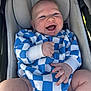 baby, infant, smiling, stroller, car_seat, blue_onesie, checkered_pattern, chubby_legs, tiny_hands, happy, portrait, candid, soft_cushion, daylight, skin, hood, diaper, playful, closeup, cheerful