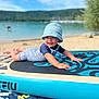 baby, child, paddleboard, beach, water, lake, hat, swimsuit, sunhat, smile, outdoor, summer, sand, sky, nature, recreation, toy, vacation, happy, portrait