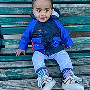 Ben a rejoint le concours — aidez-le/la à gagner de superbes lots ! bench, casual_clothing, child, curious, daylight, happy, jacket, outdoor, park, person, playful, portrait, seated, smile, sneakers, socks, toddler, weathered, wood, young