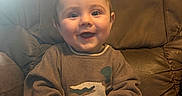 Winston is registered to the contest to win money with this photo: baby, child, cozy, cute, duck_design, expression, face, feet, hands, happy, indoor, infant, leather_chair, person, portrait, seat, skin, smiling, sweater, warm_lighting