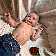 Brooks is registered to the contest to win money with this photo: baby, infant, smiling, kiss_marks, lipstick, rose, blanket, jeans, shirtless, lying_down, portrait, cheek, belly, hand, face, soft_texture, cuddly, flower, one_person, indoor
