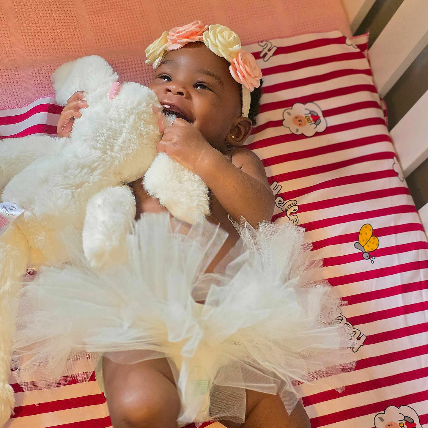 Olakamiye joined the competition — help win amazing prizes! baby, cartoon_characters, child, crib, cute, fluffy, happy, headband, indoor, infant, person, pink, sleeping_area, smiling, soft_toy, striped_sheet, teddy_bear, toy, tutu, white
