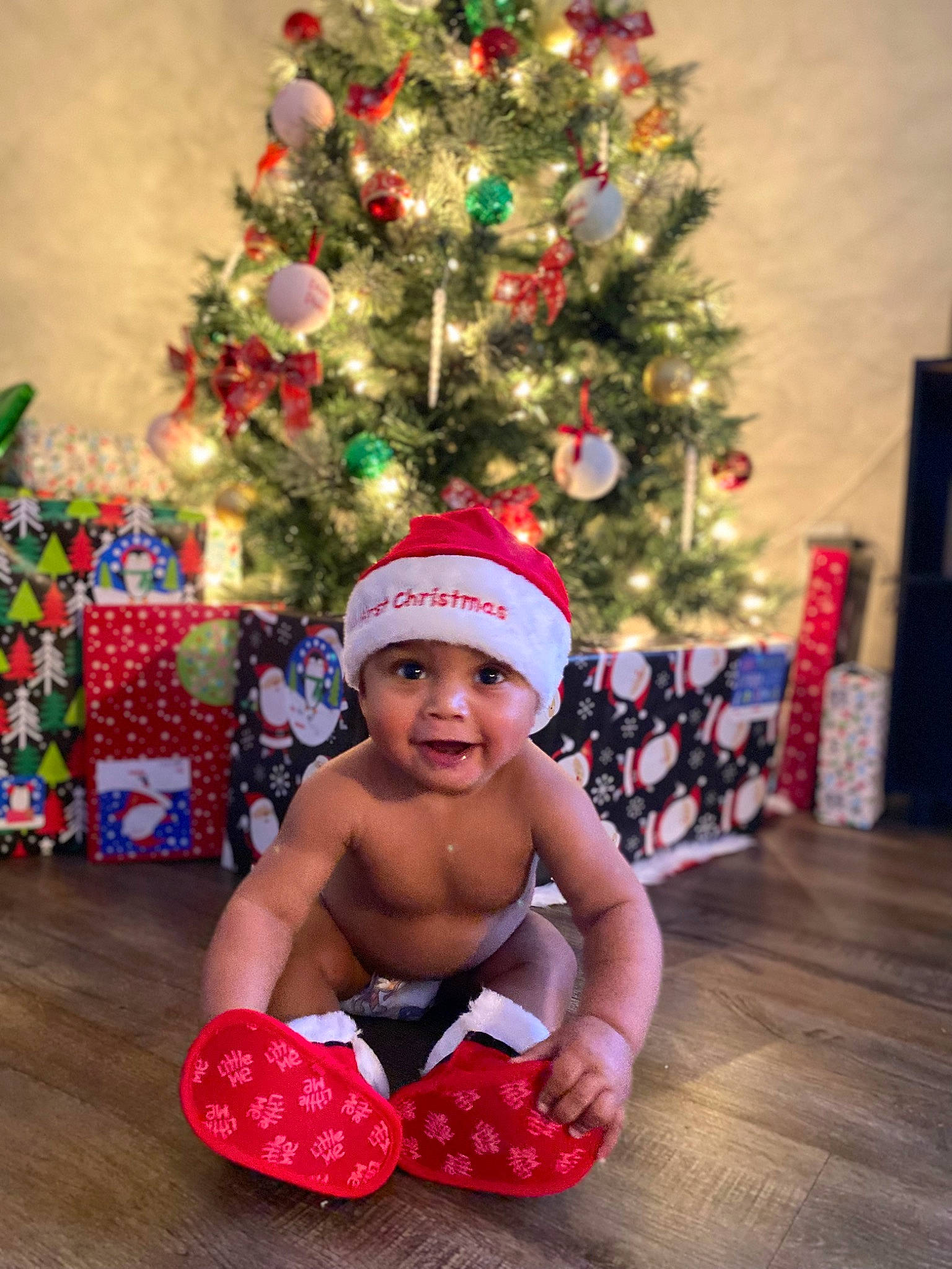 Amari is registered to the contest to win money with this photo: baby, baby_toddler_clothing, child, christmas, christmas_decoration, christmas_ornament, christmas_tree, conifer, event, fun, happy, headwear, holiday, holiday_ornament, ornament, person, plant, sitting, smile, sock