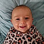 apparel, baby, blanket, cheeks, child, clothing, cute, eyes, face, happy, head, infant, leopard_print, lying_down, mouth, person, portrait, skin, smiling, young_child