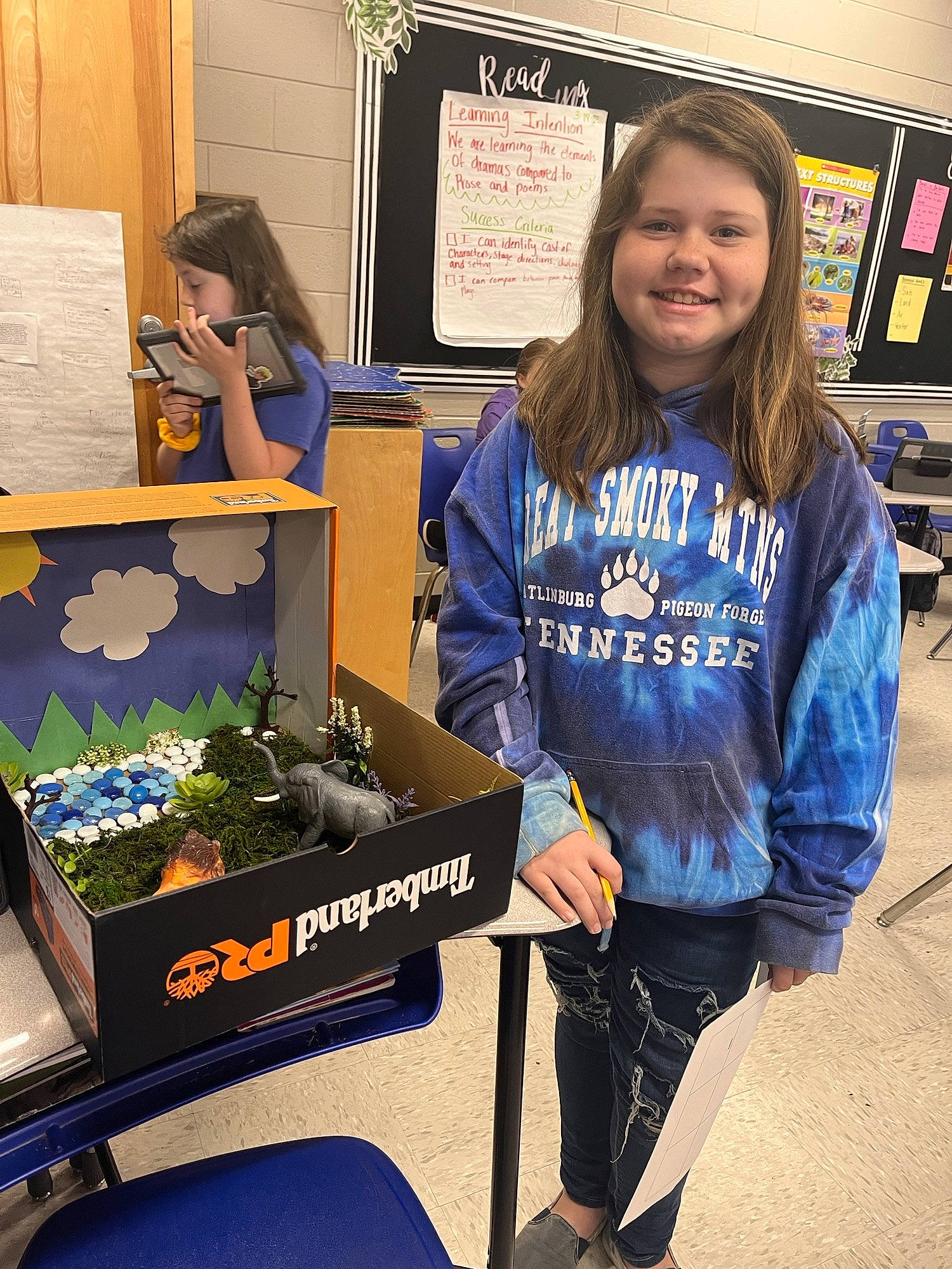 Rileigh is registered to the contest to win money with this photo: advertising, chair, community, denim, electric_blue, fun, gadget, hoodie, houseplant, job, joy, person, picture_frame, room, sitting, sleeve, smile, sportswear, t_shirt, thigh