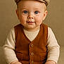 baby, child, blue_eyes, cap, vest, sweater, hands, smile, portrait, cute, innocent, seated, neutral_background, warm_colors, clothing, face, headwear, fashion, expression, studio
