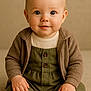 baby, child, infant, portrait, smiling, sitting, blue_eyes, blonde_hair, cozy_clothing, knitwear, neutral_background, warm_lighting, cute, hands, face, eyes, soft_texture, buttoned_outfit, socks, young