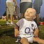 baby, child, grass, outdoor, evening, people, sportswear, england_rugby, happy, smiling, sitting, shirt, legs, feet, blurred_background, event, field, person, casual, cute