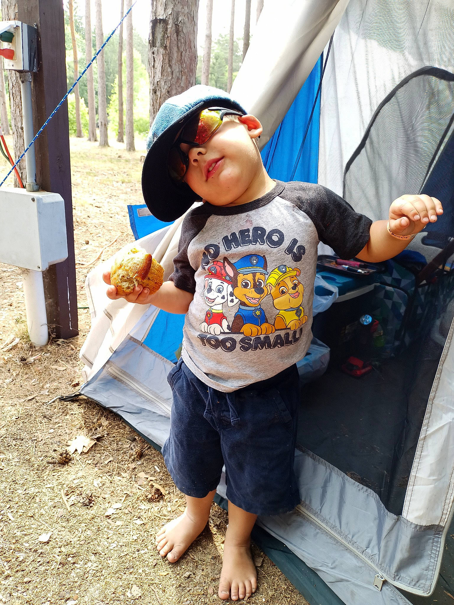 Ben is registered to the contest to win money with this photo: backpack, bag, barefoot, baseball_cap, cap, child, eyewear, fashion_accessory, food, fun, headwear, leisure, luggage_and_bags, person, play, public_space, recreation, shorts, soil, t_shirt