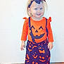 Livia a rejoint le concours — aidez-le/la à gagner de superbes lots ! child, toddler, halloween, costume, orange, black, headband, pumpkin, smiling, standing, shoes, indoor, tile_floor, wall, person, cute, festive, clothing, happy, young