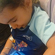 Jayden a rejoint le concours — aidez-le/la à gagner de superbes lots ! child, curly_hair, tablet, blue_case, sitting, couch, arm, bracelet, clothing, patterned_fabric, indoor, technology, screen, person, casual, focused, young, device, relaxing, home