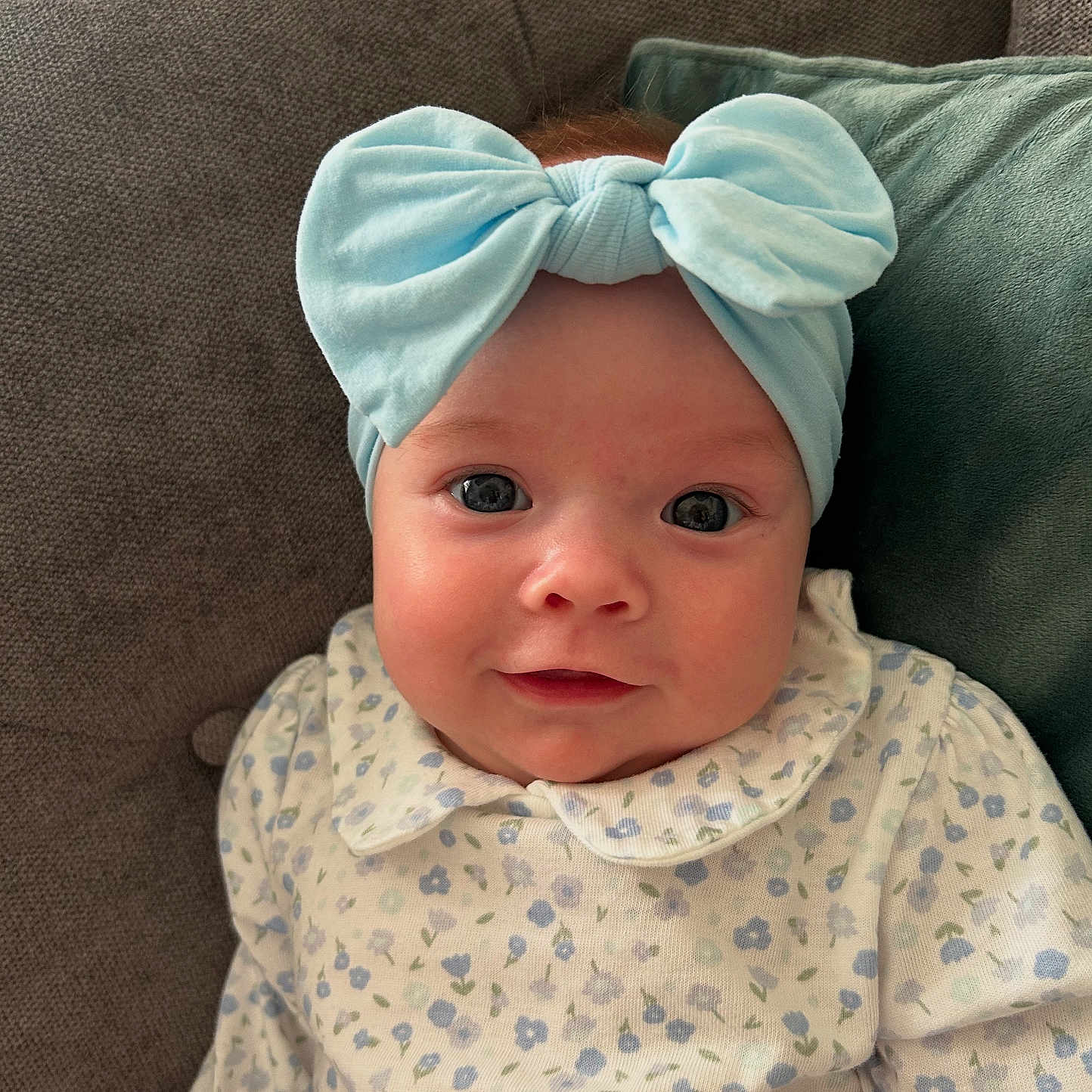Clodagh joined the competition — help win amazing prizes! baby, bow, child, clothing, couch, cute, eyes, face, floral, happy, headband, indoors, infant, pattern, pillow, portrait, sitting, smile, soft_lighting, young