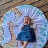 Carrusela joined the competition — help win amazing prizes! baby, infant, smiling, denim_dress, mittens, pigtails, giraffe_illustration, playmat, wooden_floor, round_mat, leaves, happy, cute, child, portrait, indoors, flooring, lying_down, person, baby_clothing