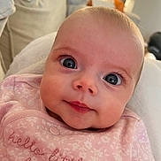 Bella joined the competition — help win amazing prizes! baby, infant, face, eyes, pink_clothing, smile, closeup, portrait, blanket, soft, indoor, cute, child, young, apparel, expression, skin, head, eyelashes, newborn