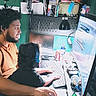 adult, child, computer, headphones, desk, monitor, keyboard, mouse, chair, room, lamp, collectibles, beard, curly_hair, technology, gaming, screen, sitting, indoor, focus