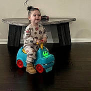 Atreus joined the competition — help win amazing prizes! child, toddler, toy_car, indoor, floor, table, wooden_floor, smiling, cute, playful, pony_tail, boots, pajamas, colorful, glowing_eyes, furniture, person, happy, young_child, home
