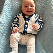 Corey is registered to the contest to win money with this photo: baby, smiling, child, sitting, blanket, blue, cardigan, striped, white_pants, socks, happy, portrait, indoor, cozy, cute, infant, soft_texture, knitted_clothing, face, person