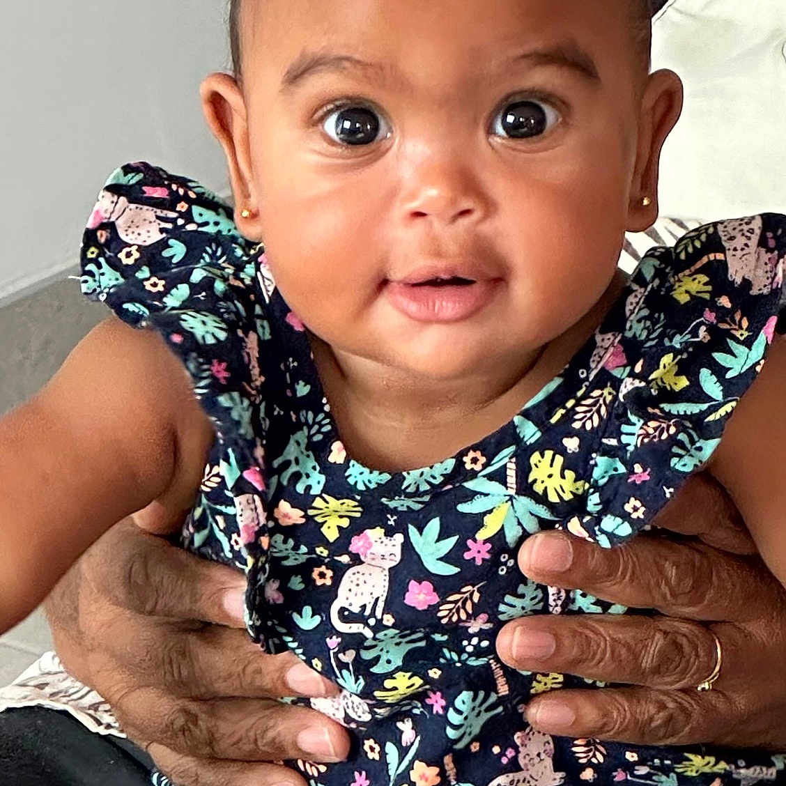 Kelane a rejoint le concours — aidez-le/la à gagner de superbes lots ! adult_hands, animal_print, baby, child, closeup, clothing, cute, earrings, expression, face, floral_pattern, hands, holding, indoor, infant, patterned_dress, person, portrait, skin, wide_eyes