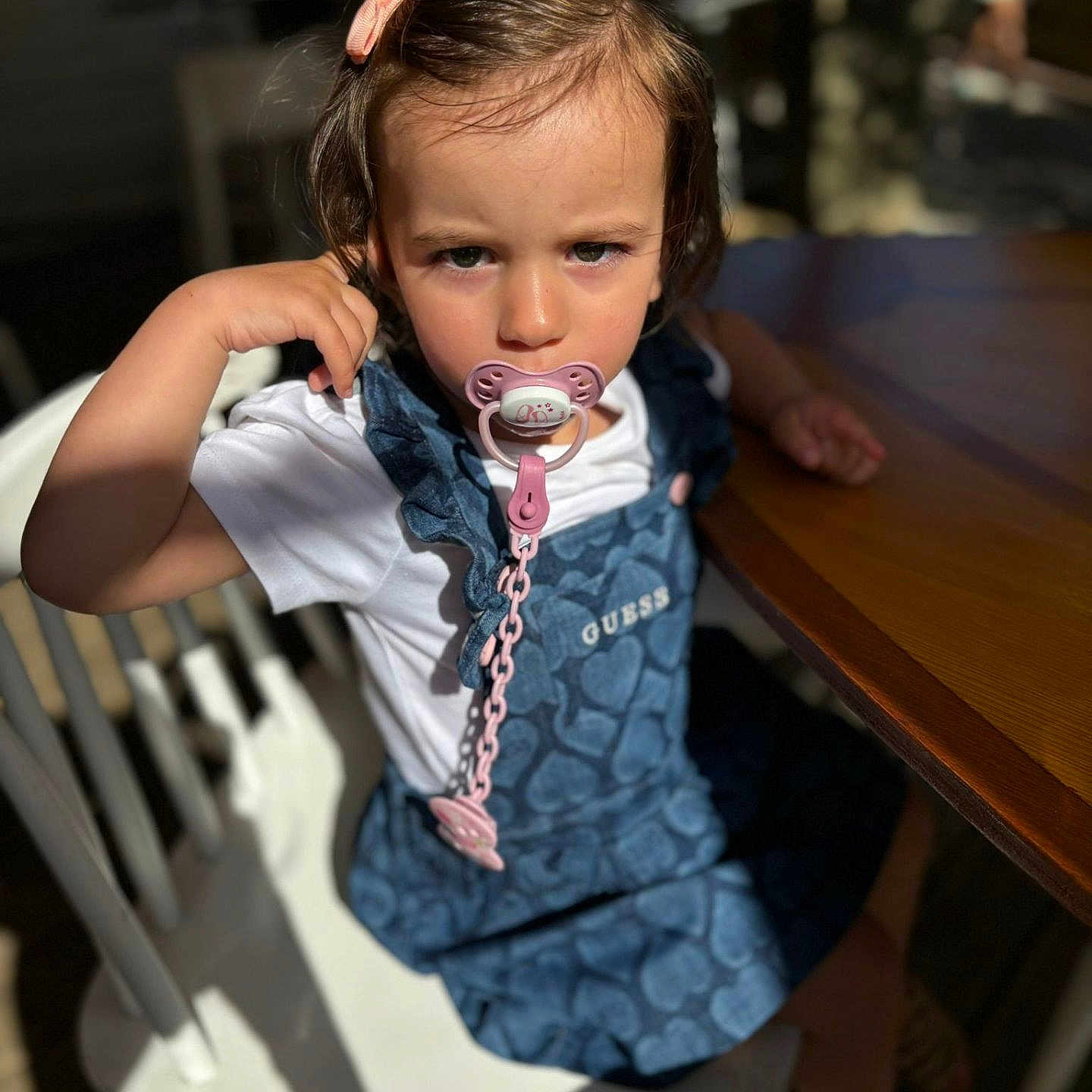 Neïa a rejoint le concours — aidez-le/la à gagner de superbes lots ! blue_dress, casual_clothing, chair, child, cute, daylight, expression, face, furniture, hair_clip, indoor, pacifier, person, shadow, sitting, sunlight, table, toddler, white_tshirt, young