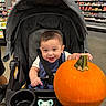 Aaron joined the competition — help win amazing prizes! baby, child, stroller, pumpkin, grocery_store, indoors, portrait, smiling, happy, infant, autumn, halloween, produce, shopping, seated, bib, harness, pacifier, store_shelves, orange