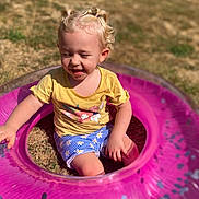 Leotie joined the competition — help win amazing prizes! blonde_hair, casual_clothing, child, confetti_inside_ring, daylight, grass, happy, inflatable_ring, nature, outdoor, pigtails, pink, play, shorts, sitting, smiling, summer, sunlight, toddler, yellow_shirt