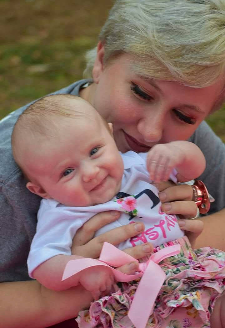 Astrid is registered to the contest to win money with this photo: baby, baby_toddler_clothing, cheek, child, event, finger, fun, gesture, grass, happy, interaction, joy, lip, nail, people_in_nature, person, pink, sitting, skin, smile
