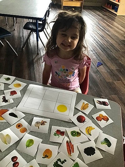 Isabelle is registered to the contest to win money with this photo: chair, child, comfort_food, cuisine, dish, finger_food, floor, flooring, font, fun, illustration, joy, person, play, recipe, smile, t_shirt, table, tableware, toddler