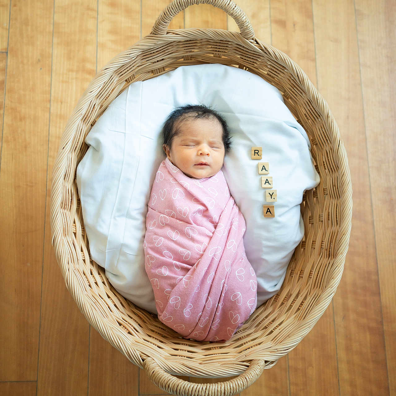 Raaya joined the competition — help win amazing prizes! newborn, baby, basket, blanket, pink, wooden_floor, wooden_blocks, letters, sleeping, cute, infant, swaddled, heart_pattern, white_cushion, indoors, peaceful, portrait, cozy, resting, child