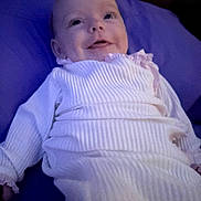 Wrenly is registered to the contest to win money with this photo: baby, infant, smile, lying_down, onesie, pillow, blanket, portrait, indoors, cute, cheeks, eyes, hands, fabric, soft_lighting, bed, gown, newborn, happy, head