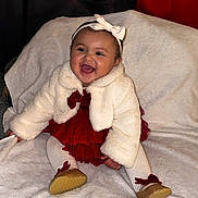 Lillian is registered to the contest to win money with this photo: baby, child, smile, white_jacket, red_dress, headband, bow, tights, golden_shoes, blanket, happy, sitting, cute, indoors, portrait, infant, fashion, warm_clothing, cheerful, adorable