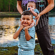 Naveen joined the competition — help win amazing prizes! children, baby, toddler, smiling, outdoor, lakeside, sunset, family, portrait, siblings, infant, playful, holding, blue_clothing, striped_clothing, water, trees, reflection, nature, happy