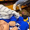 Naveen is registered to the contest to win money with this photo: child, toddler, sleeping, blue_clothing, blanket, zipper, hands, gloves, shoes, indoor, wooden_floor, portrait, close_up, relaxed, cozy, fashion, soft_blanket, playful, resting, photography