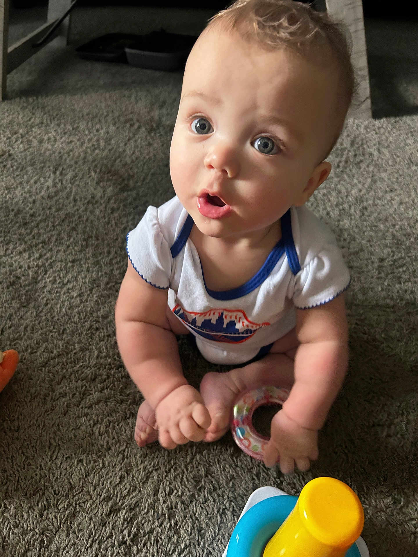 Joey joined the competition — help win amazing prizes! baby, child, carpet, toy, ring_toy, sitting, curious, blue_eyes, indoor, clothing, short_sleeve, infant, cute, person, closeup, hand, foot, expression, floor, play