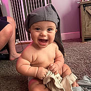 Joey joined the competition — help win amazing prizes! baby, child, hat, carpet, clothing, indoor, furniture, baby_gate, smiling, happy, cute, person, sitting, toddler, floor, room, skin, hand, foot, expression