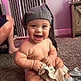 baby, child, hat, carpet, clothing, indoor, furniture, baby_gate, smiling, happy, cute, person, sitting, toddler, floor, room, skin, hand, foot, expression