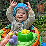 Joey is registered to the contest to win money with this photo: baby, child, hat, blue_hat, baby_walker, toy, outdoor, garden, greenery, smiling, happy, infant, clothing, striped_shirt, play, cute, hands_up, plastic_toy, seat, nature